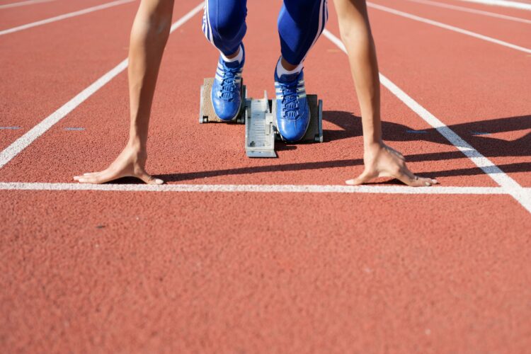 A college athlete, frozen at the start line, waiting to start a race at the track field.